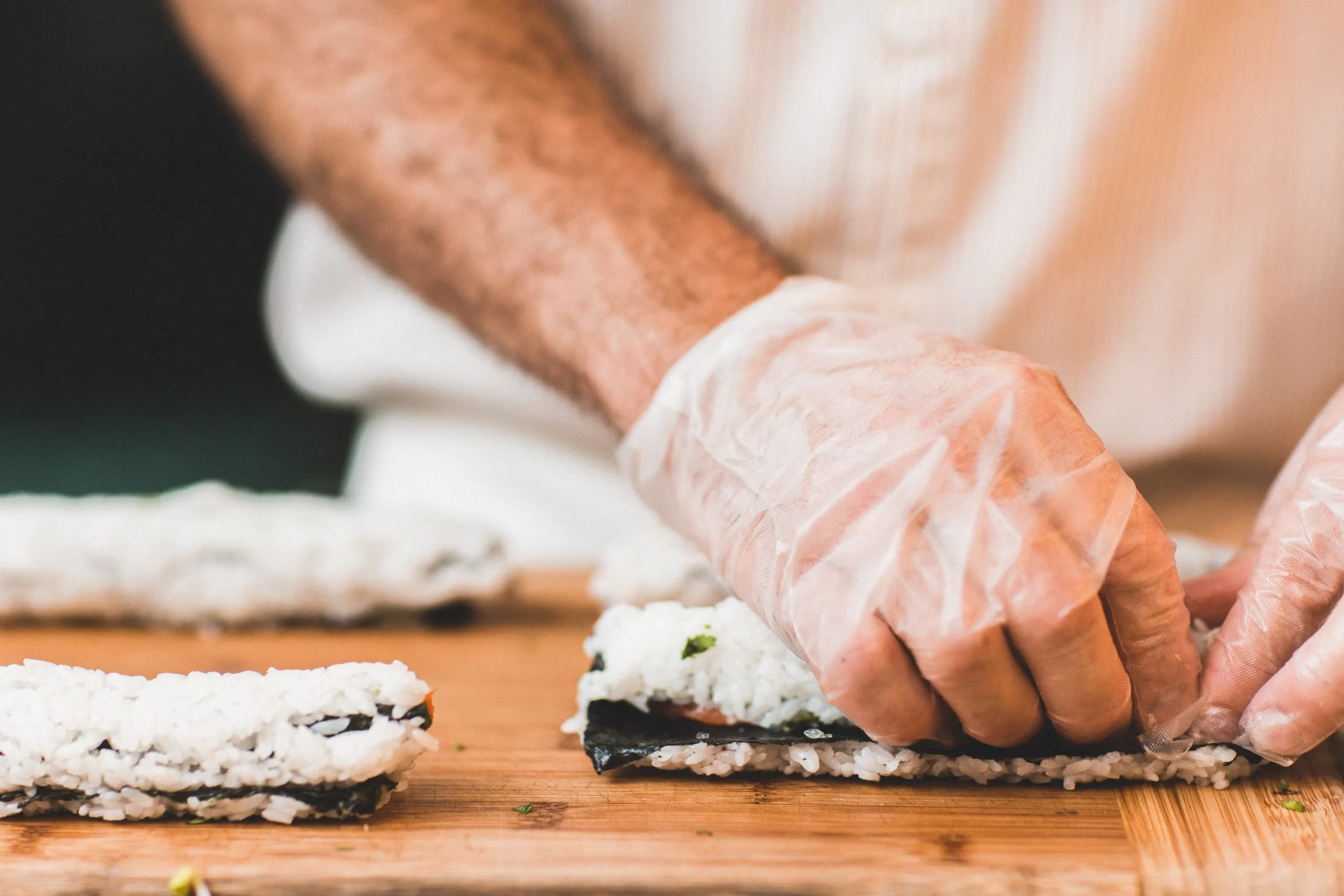 Cuisinier avec des gants qui préparent des sushis